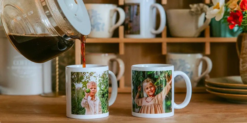 Deux mugs blancs personnalisés avec des photos sur un plan de travail, près d'une cafetière