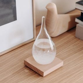 Baromètre à cristaux en forme de goutte transparente sur un socle en bois