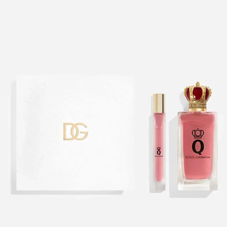 Coffret cadeau Dolce & Gabbana Q by Dolce & Gabbana composé d'un flacon d'eau de parfum à bouchon couronne dorée et rouge, d'un vaporisateur de voyage, et d'une boîte blanche estampillée du monogramme DG doré, sur fond blanc.