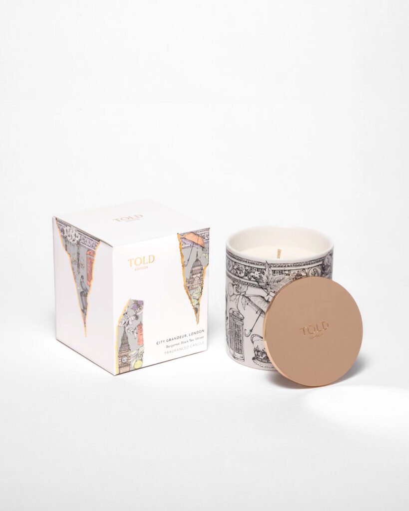 Bougie parfumée City Grandeur London dans son pot en porcelaine illustré avec couvercle doré, présentée aux côtés de son coffret d'emballage Told London.
